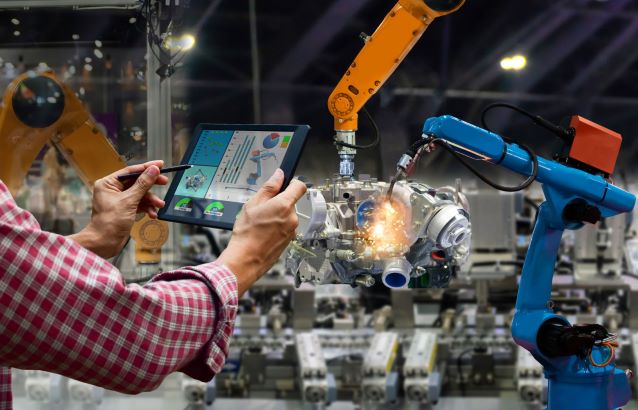 Technician holding control screen in front of mechanical arm 