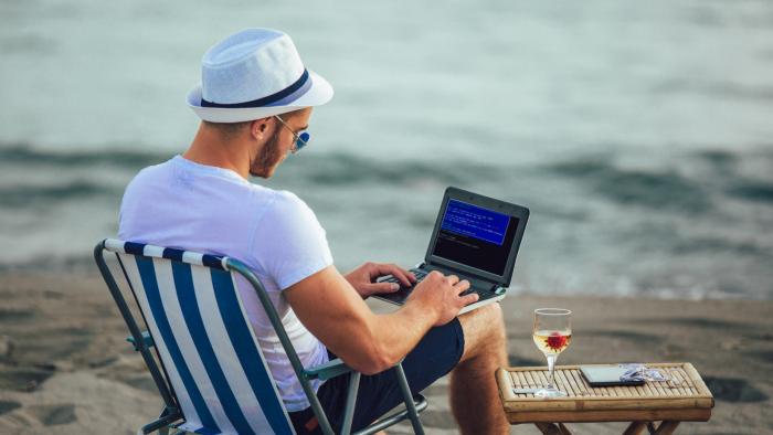 Man working on a laptop at the beach