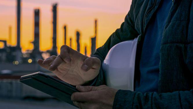 Engineer using tablet near oil refiner