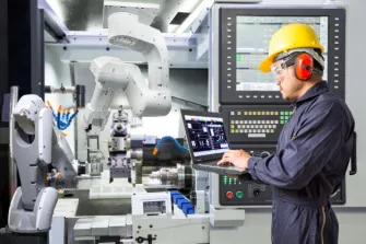 engineer working on laptop with robotic arm